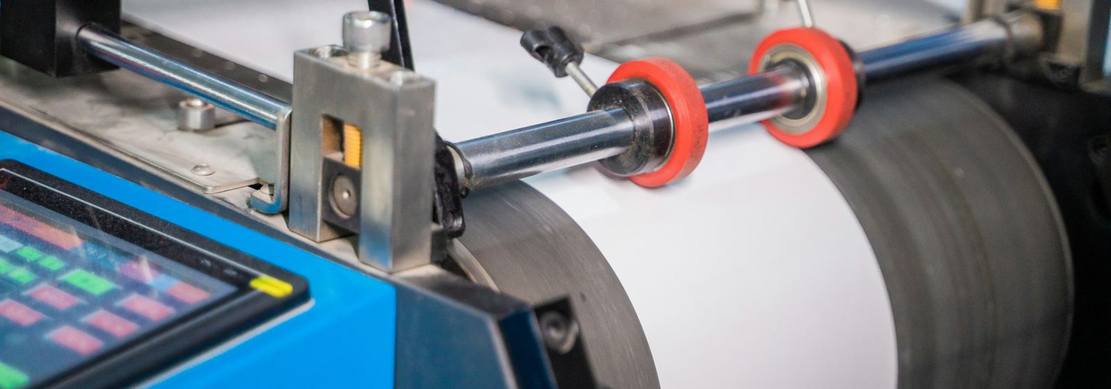 Bobina de papel en una máquina de impresión con rodillos y panel de control